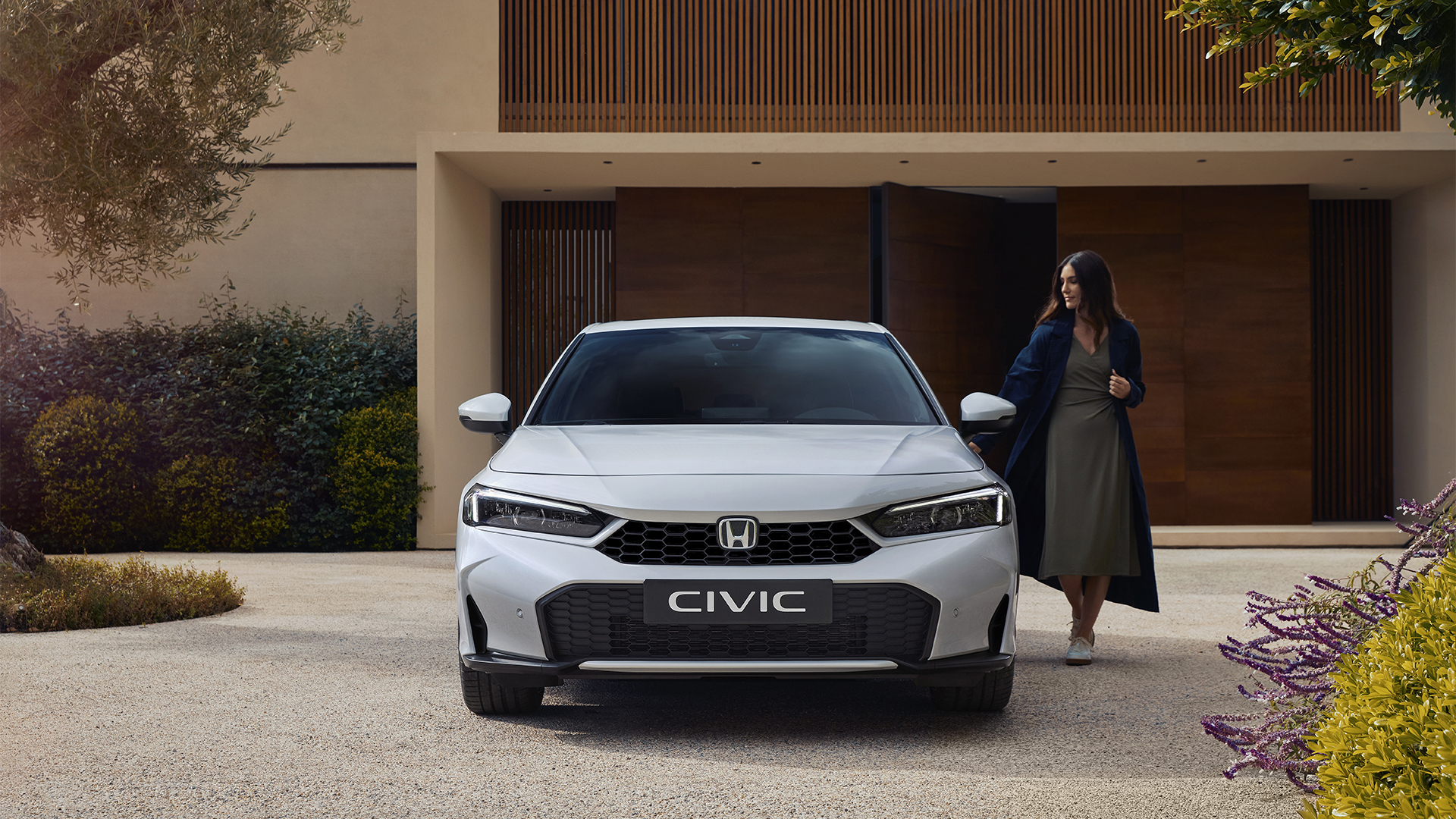 Predný pohľad na Civic Hybrid so ženou otvárajúcou dvere.