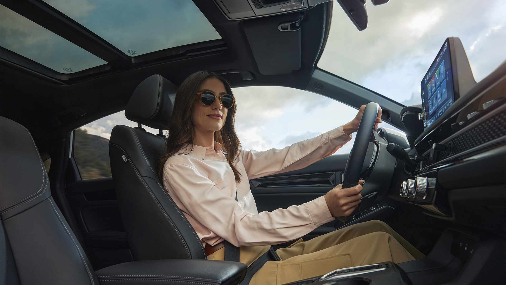 Žena v slnečných okuliaroch s rukami na volante Civicu Hybrid
