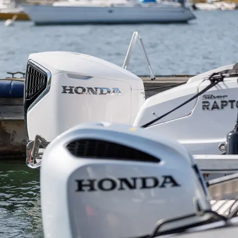 Skupina ľudí skáčucich do vody z člna Honwave s motorom Honda na jazere.