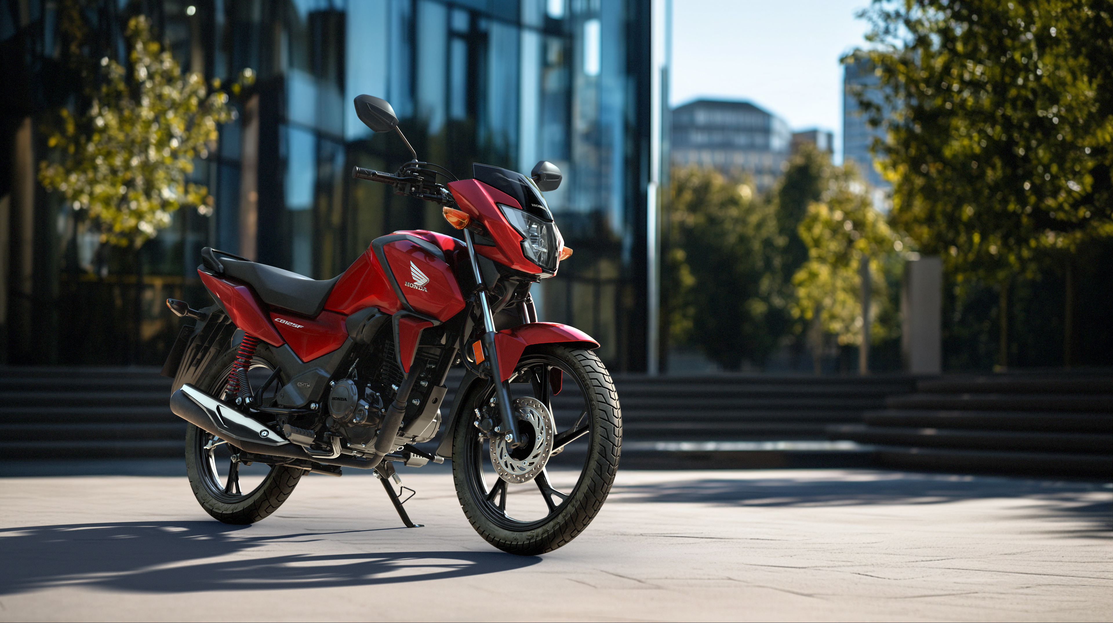 Trojštvrťový pohľad spredu z ľavej strany na červený stroj CB125F na mestskej ceste