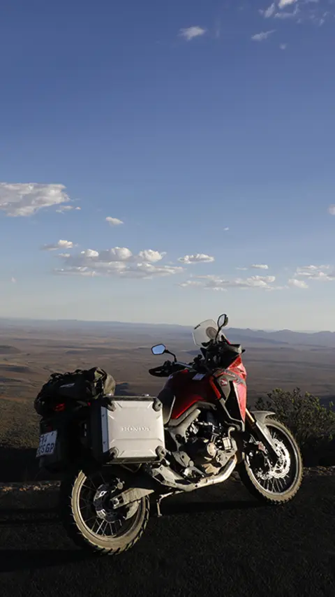 Motocykel Honda CRF1000L Africa Twin zaparkovaný na ceste s výhľadom na púšť Karoo.