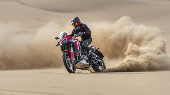 Trojštvrťový predný záber z ľavej strany na model Honda Africa Twin pri jazde v piesku