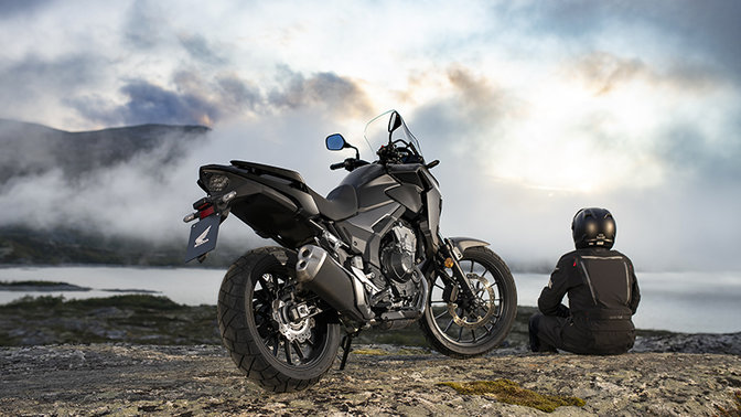 CB500X, trojštvrťový zadný pohľad sprava vedľa sediaceho jazdca v horách