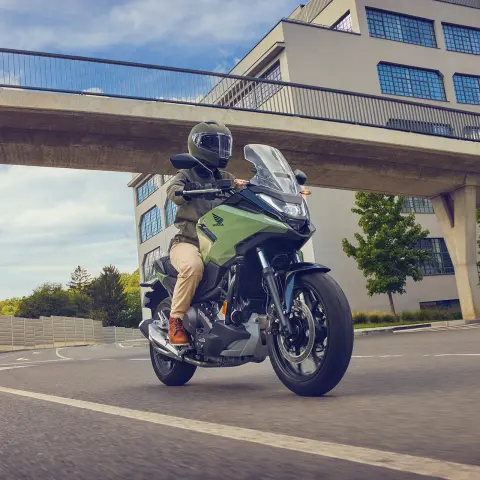 Figurant pri jazde na motocykli Honda NC750X v meste.