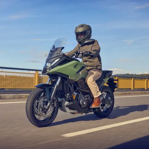 Bočný záber na figuranta idúceho na motocykli Honda NC750X po diaľnici