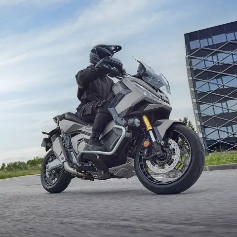 Záber na skúter X-ADV z boku na kruhovom objazde v meste