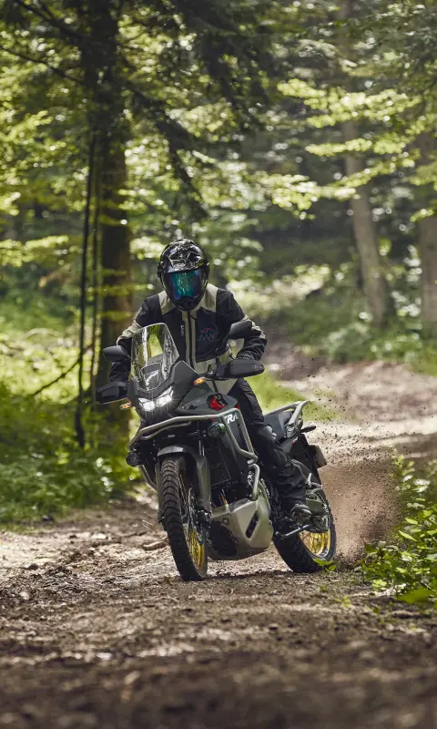 Model jazdiaci na motocykli XL750 Transalp v lese.