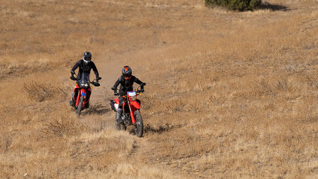 Terénny motocykel Honda, predný 3/4 pohľad, jazda po prašnej ceste.