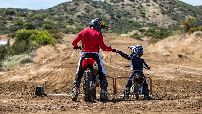 Pohľad zozadu na modely Honda CRF50F a CRF450R v teréne