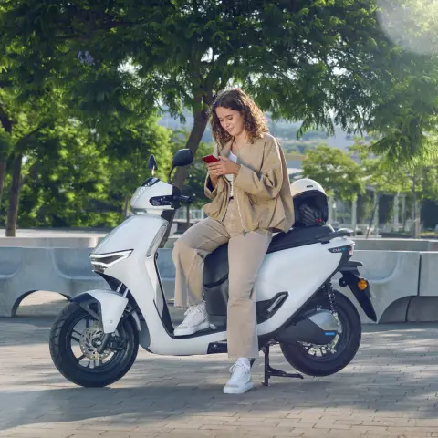 Figurant opierajúci sa o skúter Honda CUV e: v meste