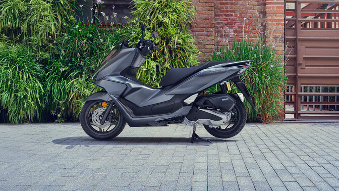 Skúter PCX 125 zaparkovaný pri zelenej ploche.