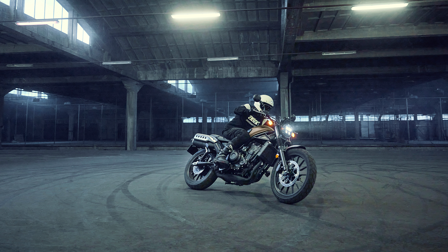 Figurant jazdí na motocykli Honda CL500 na parkovisku.