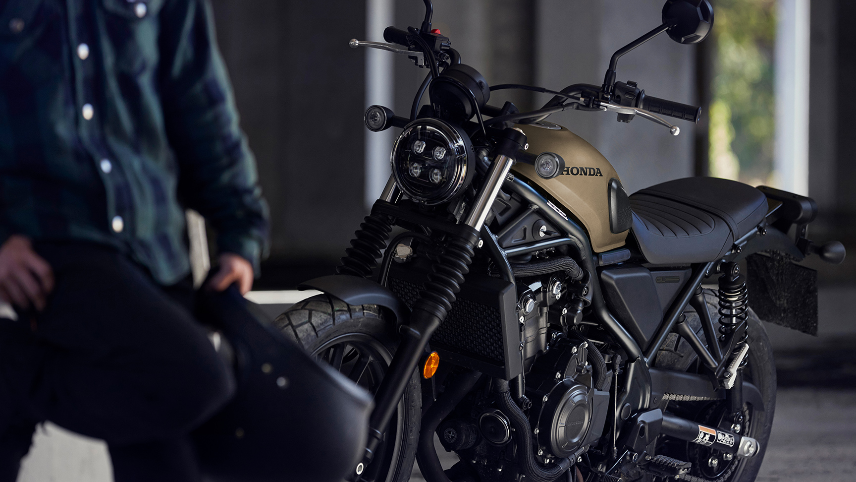 Figurant stojí vedľa motocykla CL500 v garáži.