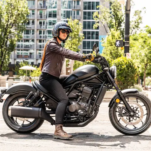Pohľad zboku na figuranta na stroji Honda CMX1100 v meste.