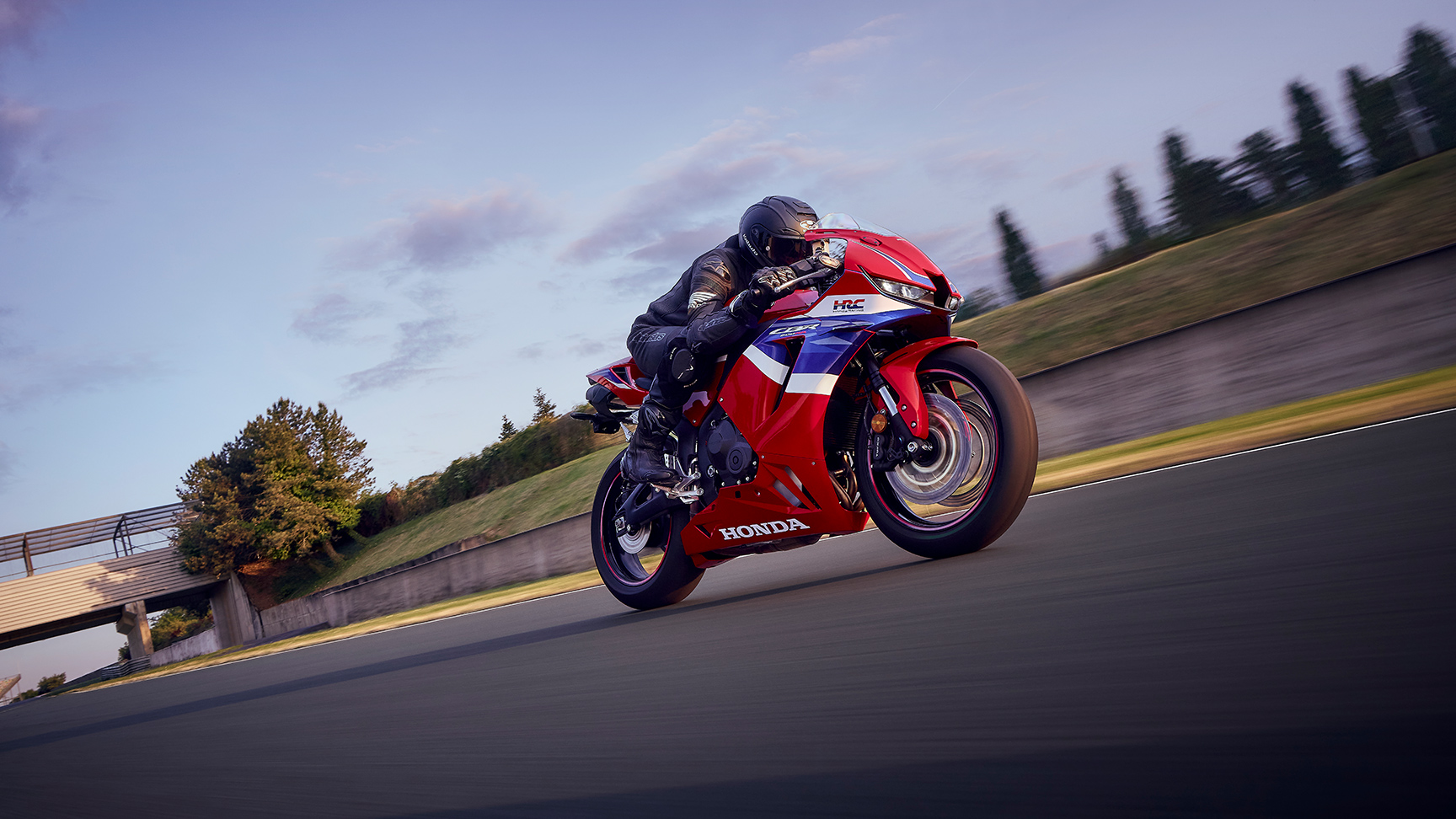 CBR600RR na okruhu s jazdcom v zákrute pri západe slnka.