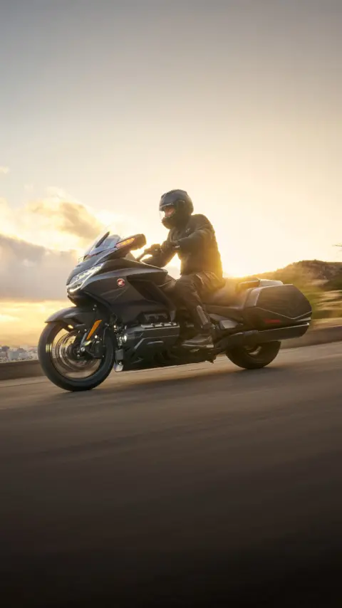 Jazdec smerujúci k zapadajúcemu slnku na Honde GL1800 Goldwing